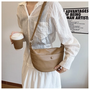 Detailed view of brown faux leather half-moon crossbody bag with adjustable strap