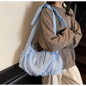 Model wearing light blue pleated nylon shoulder bag with stylish knotted strap detail