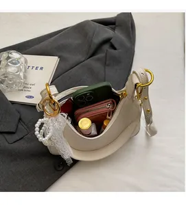 Détails de l'intérieur du sac demi-lune beige contenant téléphone, portefeuille et rouge