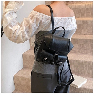 Close-up of black lychee grain mini backpack showing flap cover and silver buckle pockets