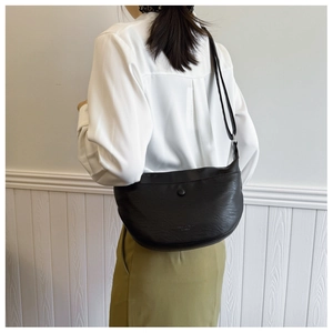 Detail of black leather hobo bag with adjustable strap and metal buckle on model