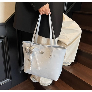 Detail of grey tote bag with heart embossing and silver silk bow with lace trim