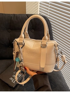 Chic off-white Boston handbag with dog charm and embossed lettering on high-quality PU leather