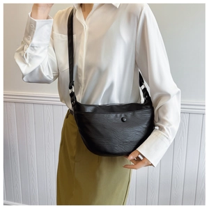 Detail of a black crescent hobo bag in textured PU leather with adjustable shoulder strap