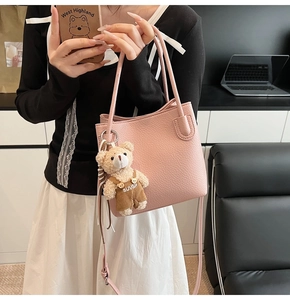 Detailed texture of pink pebble leather bucket bag with a cute plush bear charm