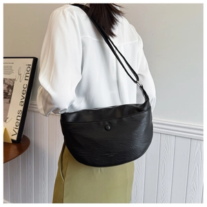 Detailed view of black crescent bag featuring smooth PU leather texture and zipper detail