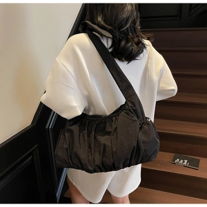 Detail view of the black ruched nylon cloud bag worn crossbody over a minimalist outfit