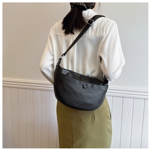 Detail shot of black semi-circle bag showing adjustable strap and silver metal buckle