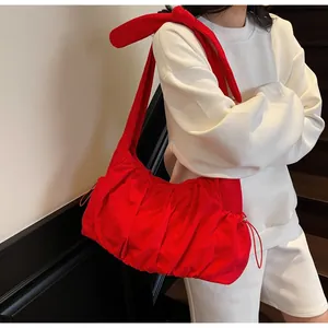 Detail of red oversized nylon tote bag with large bow shoulder strap and pleated texture