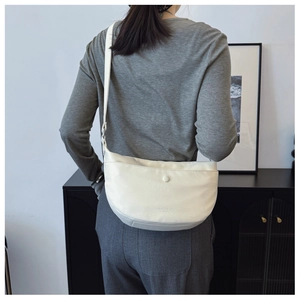 Detail showing the creamy beige leather texture and decorative buckle on the crossbody bag