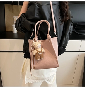 Detail of pink lychee textured tote bag with cute bear pendant and knotted handle