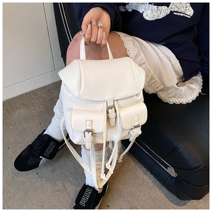 Detail of cream white pebbled leather mini backpack featuring twin pockets and metal buckles