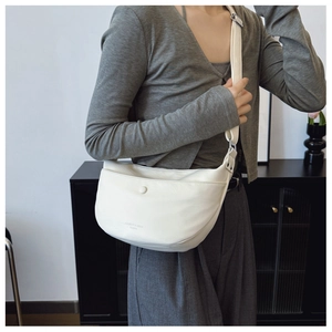 Detail of off-white dumpling bag with textured surface and magnetic snap closure