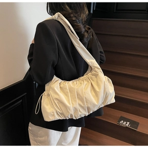Detailed texture of beige pleated nylon tote bag with drawstring side on wooden steps