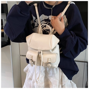 Macro detail of off-white faux leather backpack showing drawstring and flap closure
