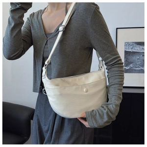 Detail view of white leather crescent bag with adjustable strap and decorative button