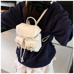 Detail view of cream mini backpack with lychee texture and buckle pockets on a model
