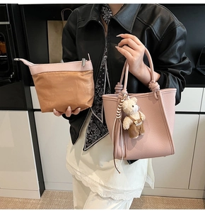 Close-up of pink litchi grain leather tote bag with bear charm and matching pouch