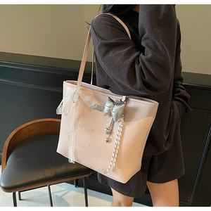 Detail of pink faux leather tote bag with heart embossing and lace bow decoration