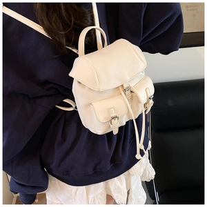 Detail of cream leather mini backpack with pebble texture and buckle pockets on the front