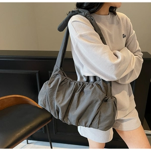 Detail of grey pleated nylon tote bag featuring a knotted shoulder strap and soft texture