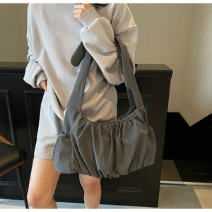 Macro view of charcoal grey pleated nylon shoulder bag with wide strap detail