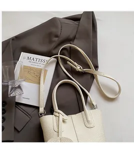 Dettaglio della borsa a secchiello in pelle bianco crema con manici e tracolla regolabile