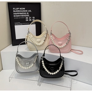 Detail van vier hobo-tassen in beige, roze, zilver en zwart met parel hart kettingen