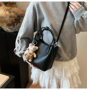 Detail of black pebbled leather bucket bag with silver metal hardware and bear charm