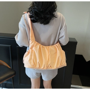 Detail view of large peach nylon shoulder bag with adjustable drawstring strap and pleated texture