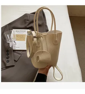 Dettaglio della borsa a secchiello beige con trama litchi e ciondolo a elefante