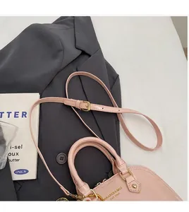 Close-up of pink shell handbag with shiny finish and adjustable long shoulder strap