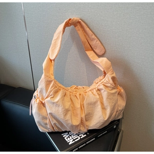 Close-up of a light orange apricot pleated nylon tote bag with drawstring details