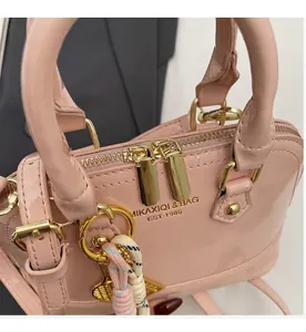 Detailed macro view of pink patent leather shell bag with gold double zippers and charm