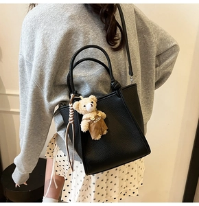 Gros plan détaillé du sac seau noir en cuir grainé avec un pendentif d'ours mignon