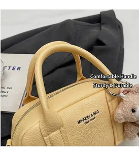 Close-up of beige lychee texture leather bowling bag with cute plush bear charm