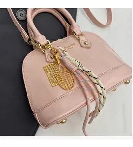 Detailed close-up of pink patent leather shell bag with gold hardware and colorful charms