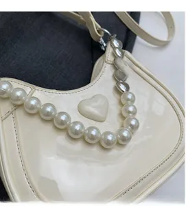 Detail van crème laklederen emmertas met parelketting en hartvormig beslag