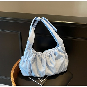 Detail view of light blue ruched cloud bag with drawstring pockets on black leather chair
