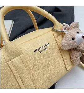Detail of lychee pattern leather and bear charm on yellow bowling handbag for women