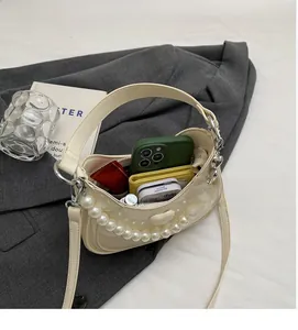 Bovenaanzicht van de crèmekleurige tas met ruime binnenkant op een grijze blazer