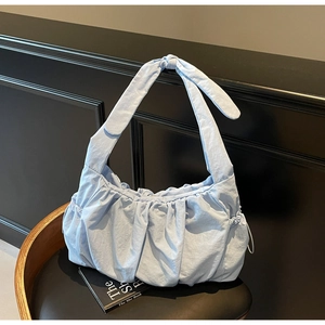 Detail of light blue pleated nylon tote bag with knot shoulder strap on dark background
