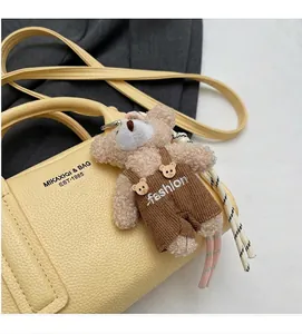 Detail of yellow lychee leather handbag with a plush bear charm and brand logo