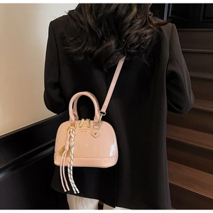 Pink patent leather shell bag shown with a black blazer in a stylish lifestyle setting