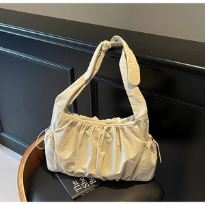 Detailed view of cream nylon tote bag with pleated texture and decorative knot strap