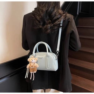 Detail of mint green pebble leather handbag with bear charm and adjustable shoulder strap