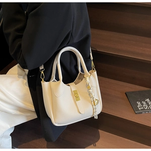 Dettaglio della borsa a mano bianco sporco con grana litchi, chiusura in metallo dorato