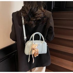 Detail view of the mint green crossbody bowling bag with a cute teddy bear charm