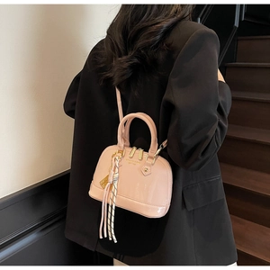 Rear view of a pink patent shell bag with silk scarf on dark wooden stairs