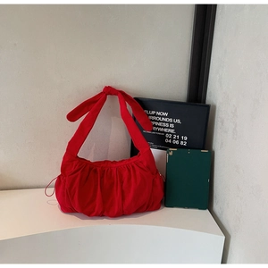 Detail of red nylon tote bag with pleated texture, bow shoulder strap and a tablet